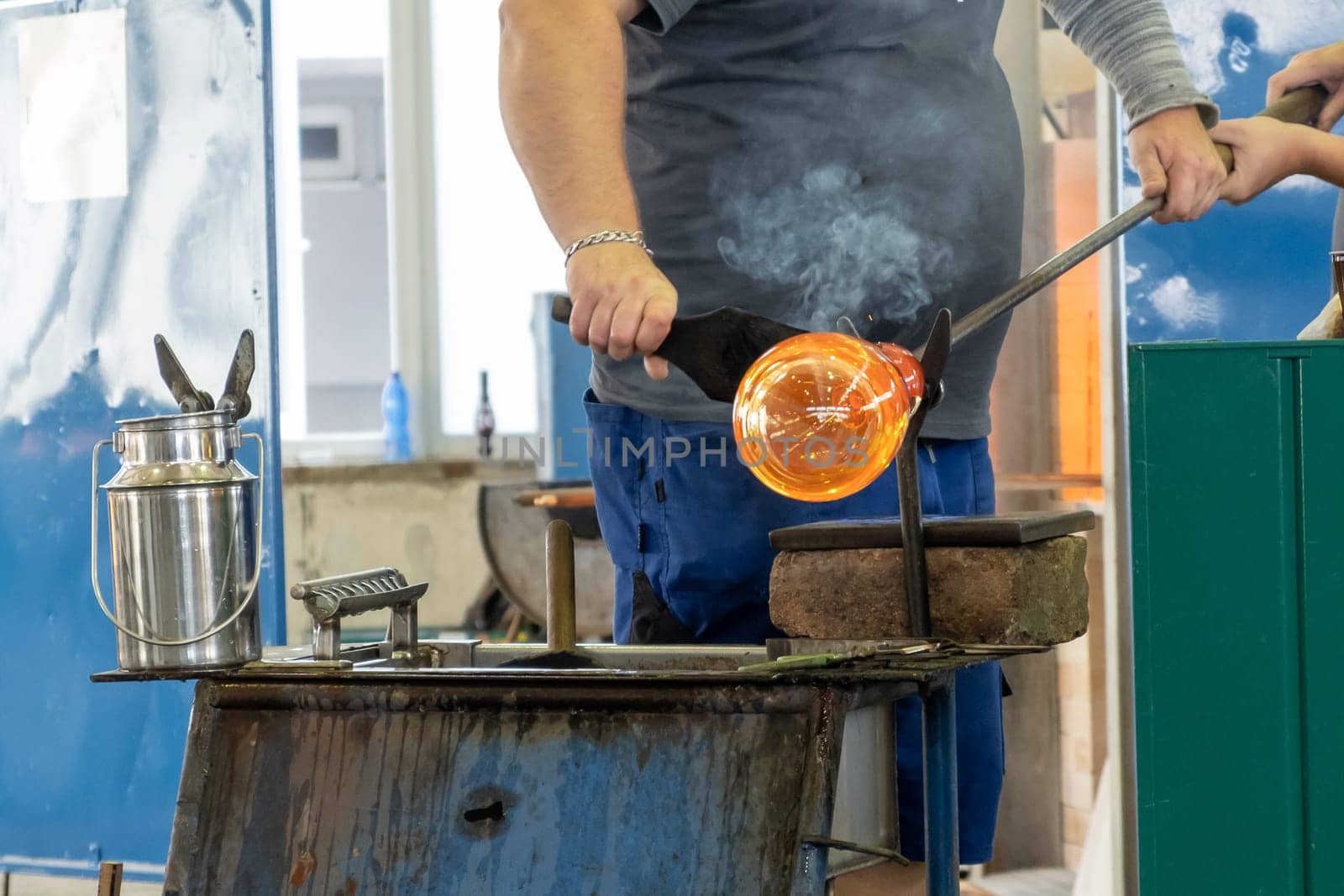 Manual glass production by glassblowing by worker at the factory.