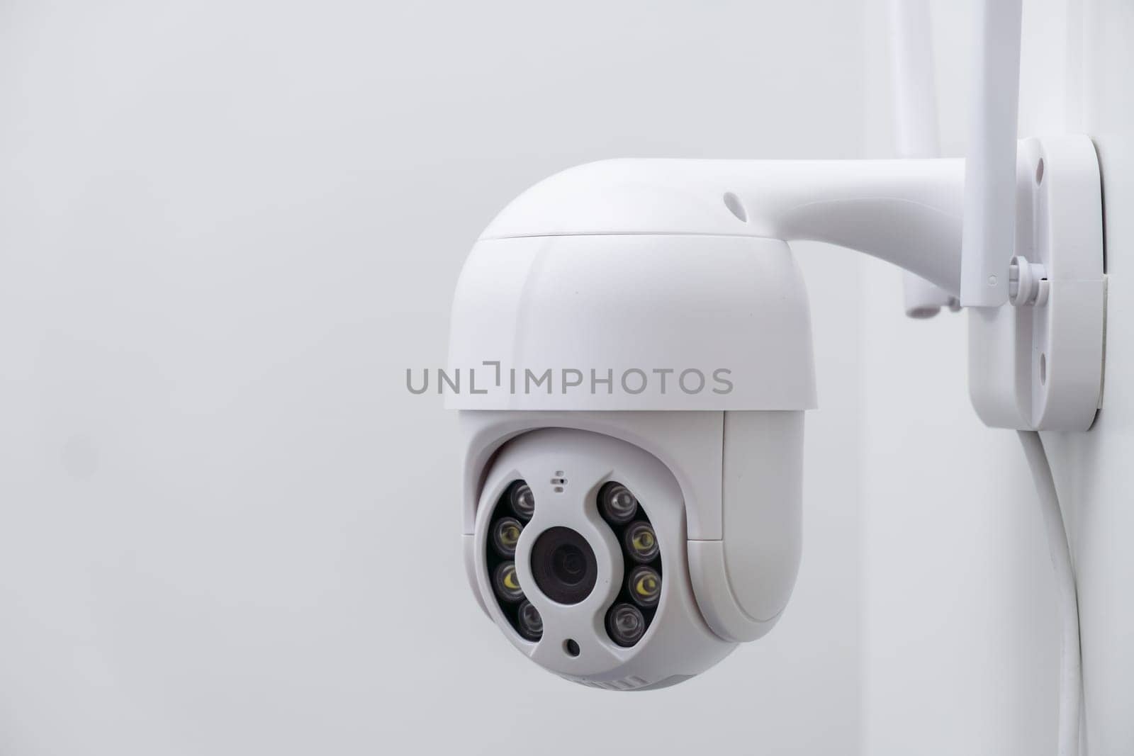 Round CCTV camera with antennas shoots video on the white wall. Digital equipment to record and broadcast real time video closeup