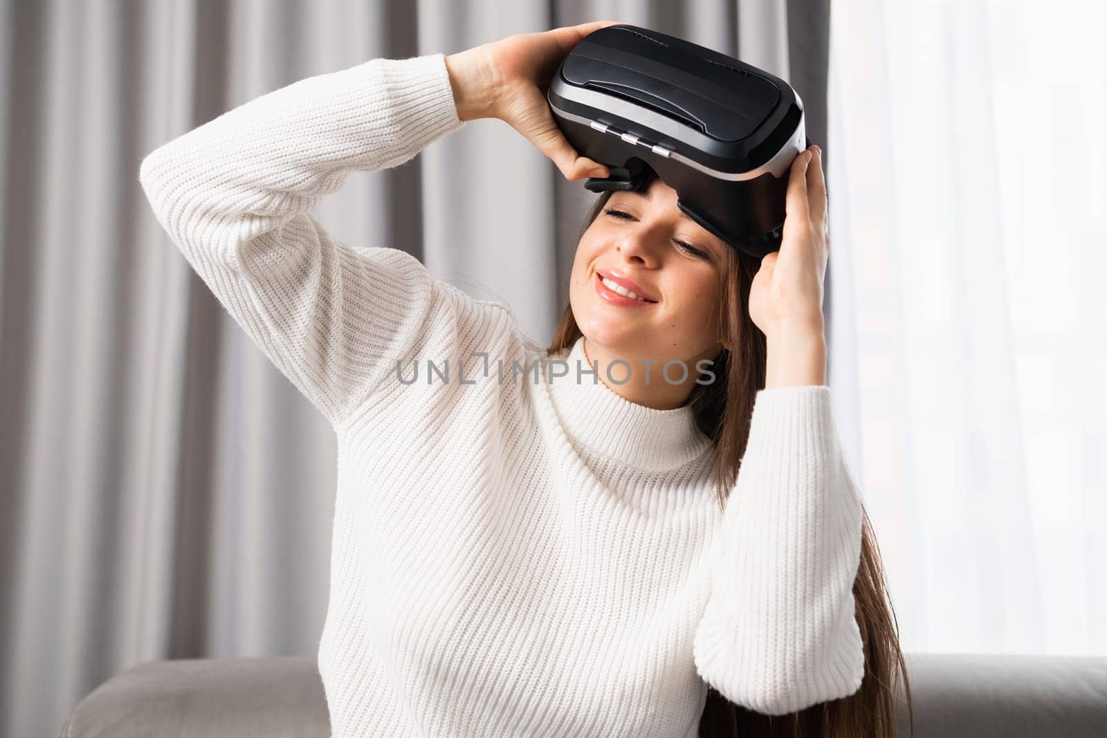 Portrait of a smiling woman putting on VR goggles for playing games in cyber space.