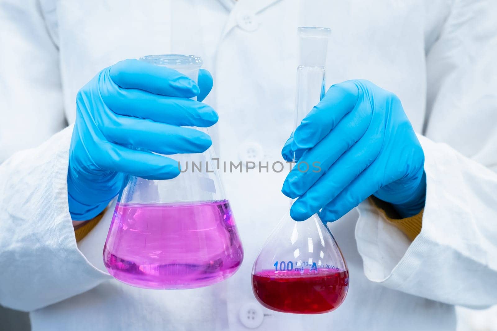 Scientist doing experiments with bright solutions in the flasks at the chemical laboratory. Researcher working in modern microbiology center.