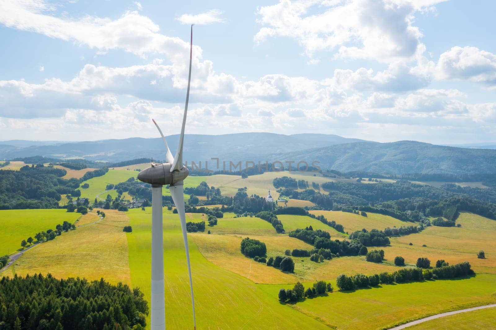 Aerial view of wind turbines propeller in the yellow field with amazing view on the mountains by vladimka
