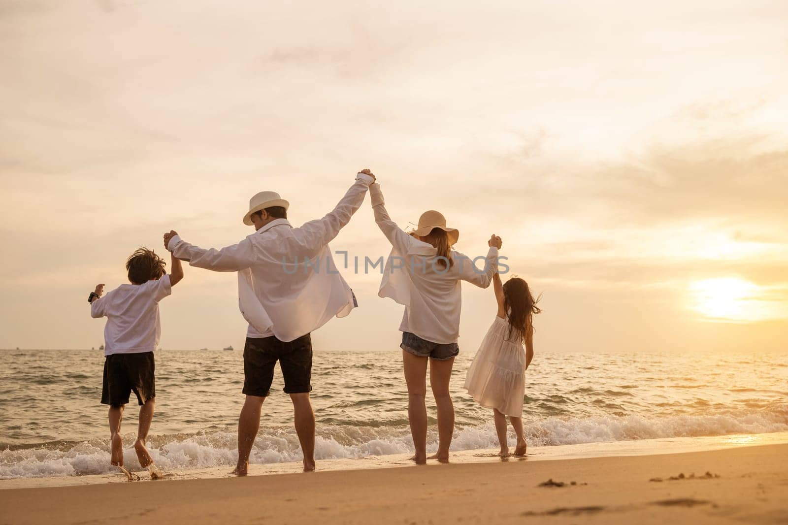 Happy Asian family have fun jumping together on beach in holiday at sunset time by Sorapop