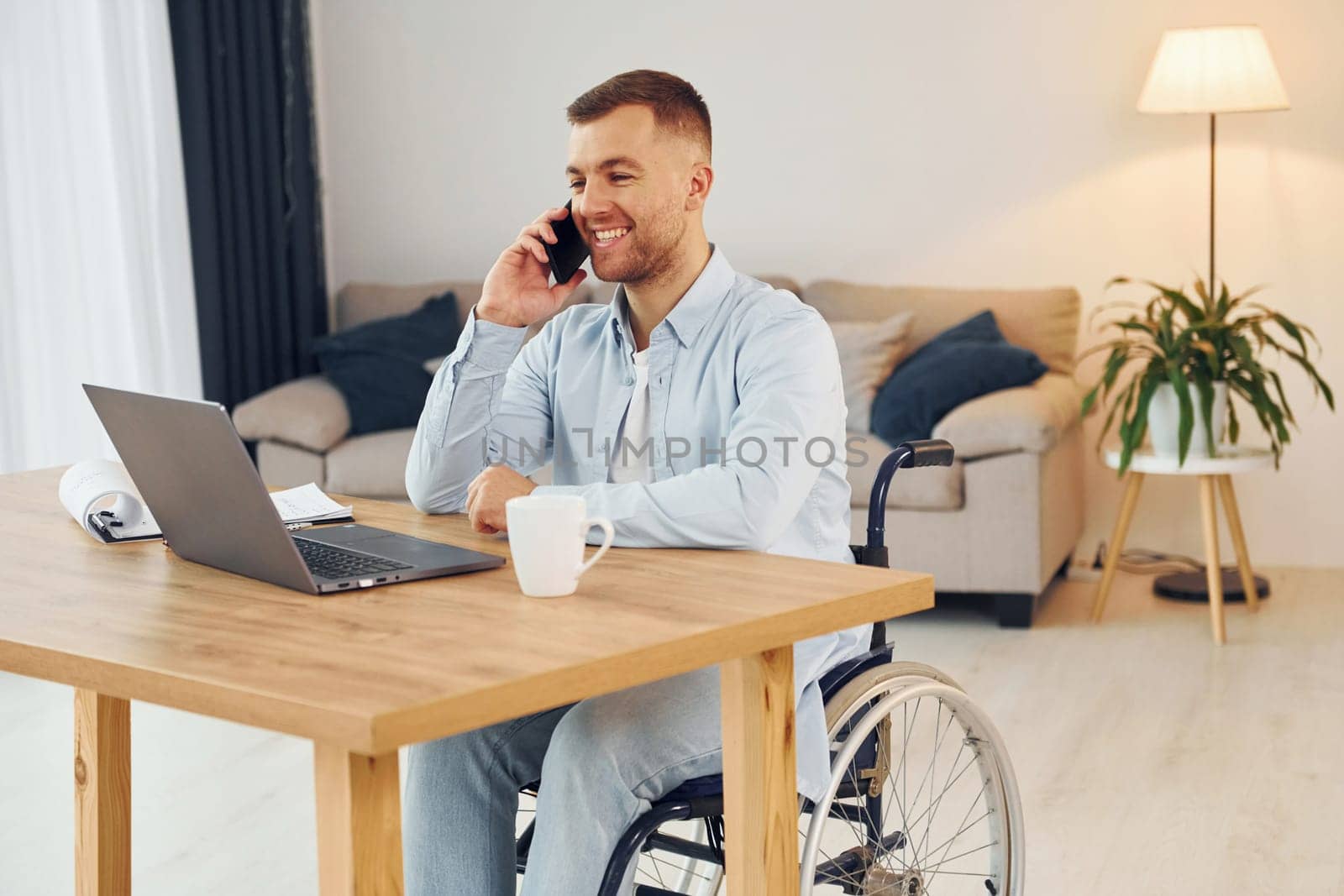 Laptop on the table. Disabled man in wheelchair is at home.