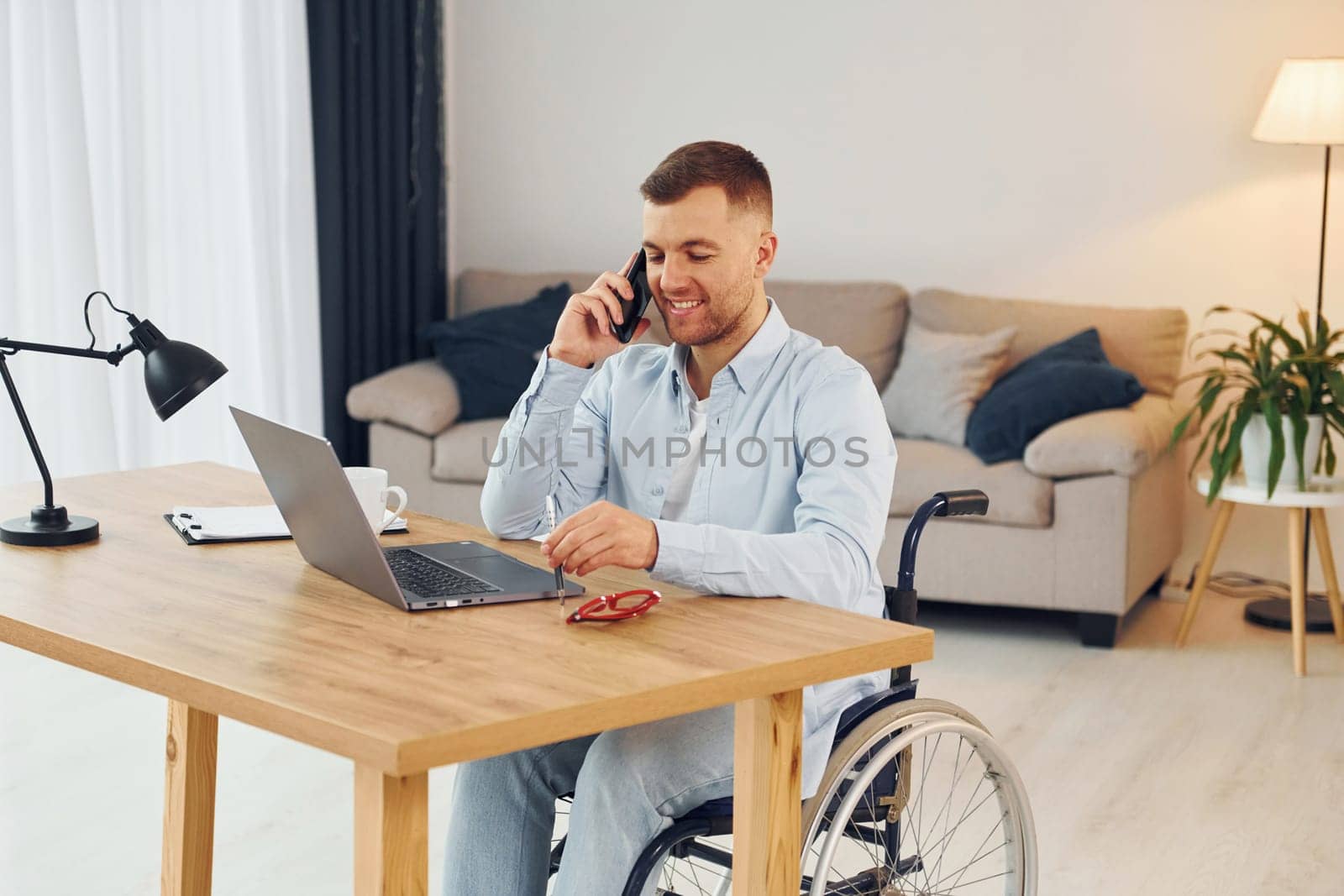 Using laptop. Disabled man in wheelchair is at home.