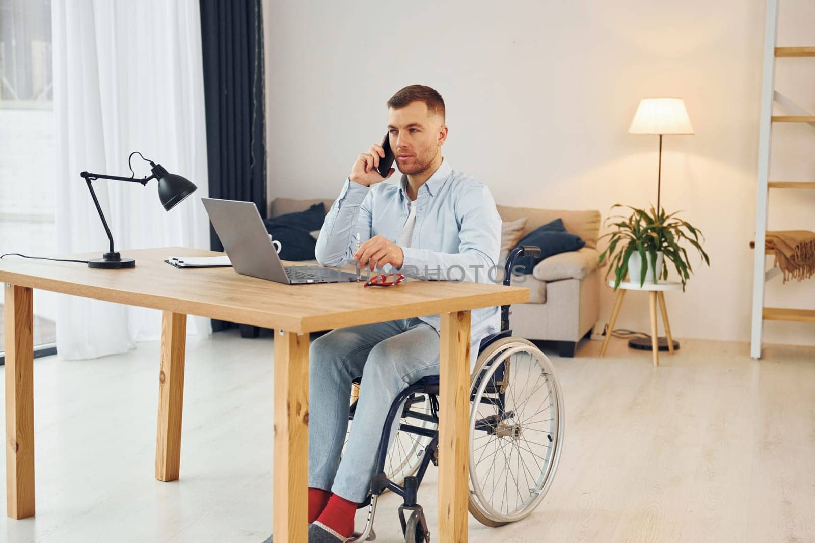 Using laptop. Disabled man in wheelchair is at home.
