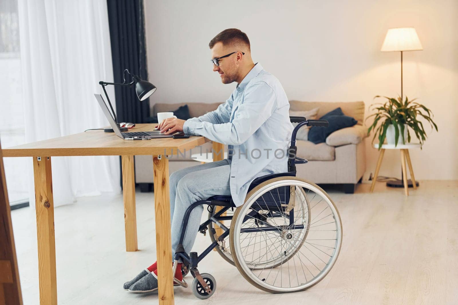 Smart freelance worker. Disabled man in wheelchair is at home.
