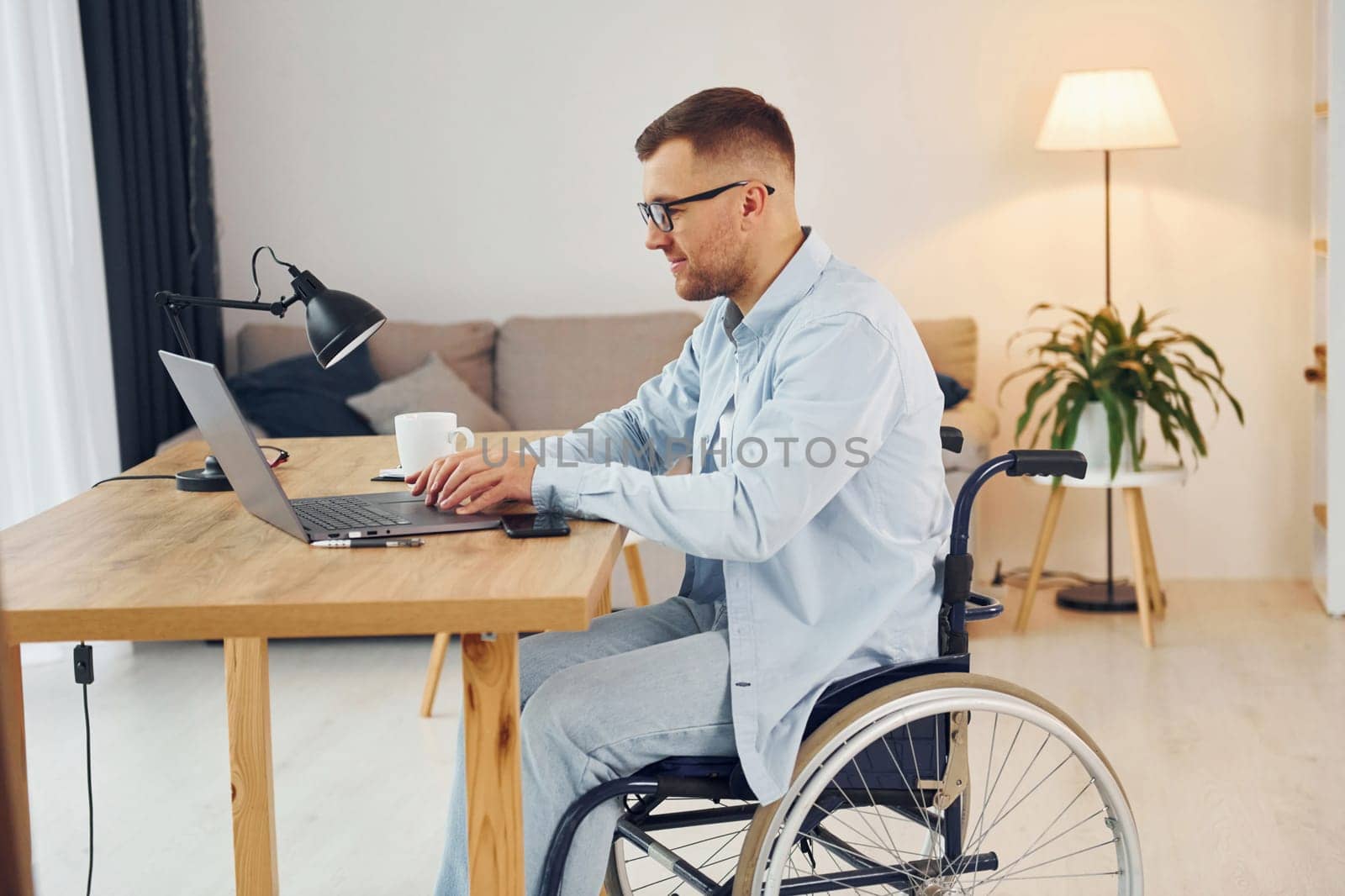 Smart freelance worker. Disabled man in wheelchair is at home.