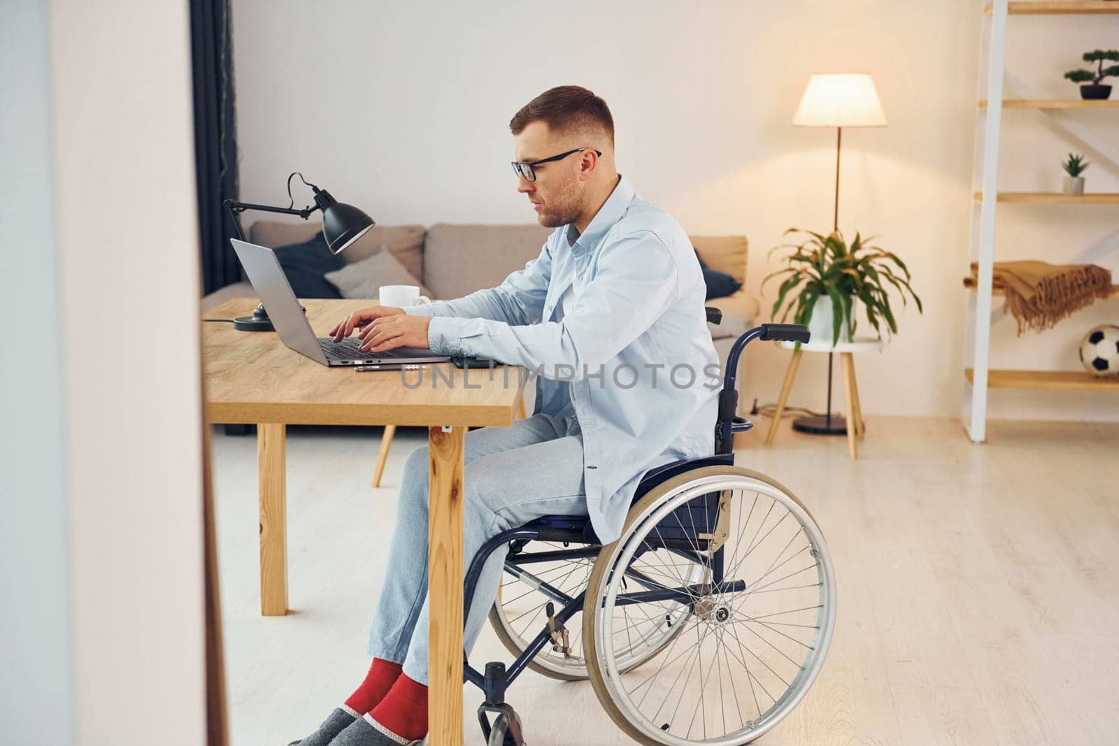 Smart freelance worker. Disabled man in wheelchair is at home.