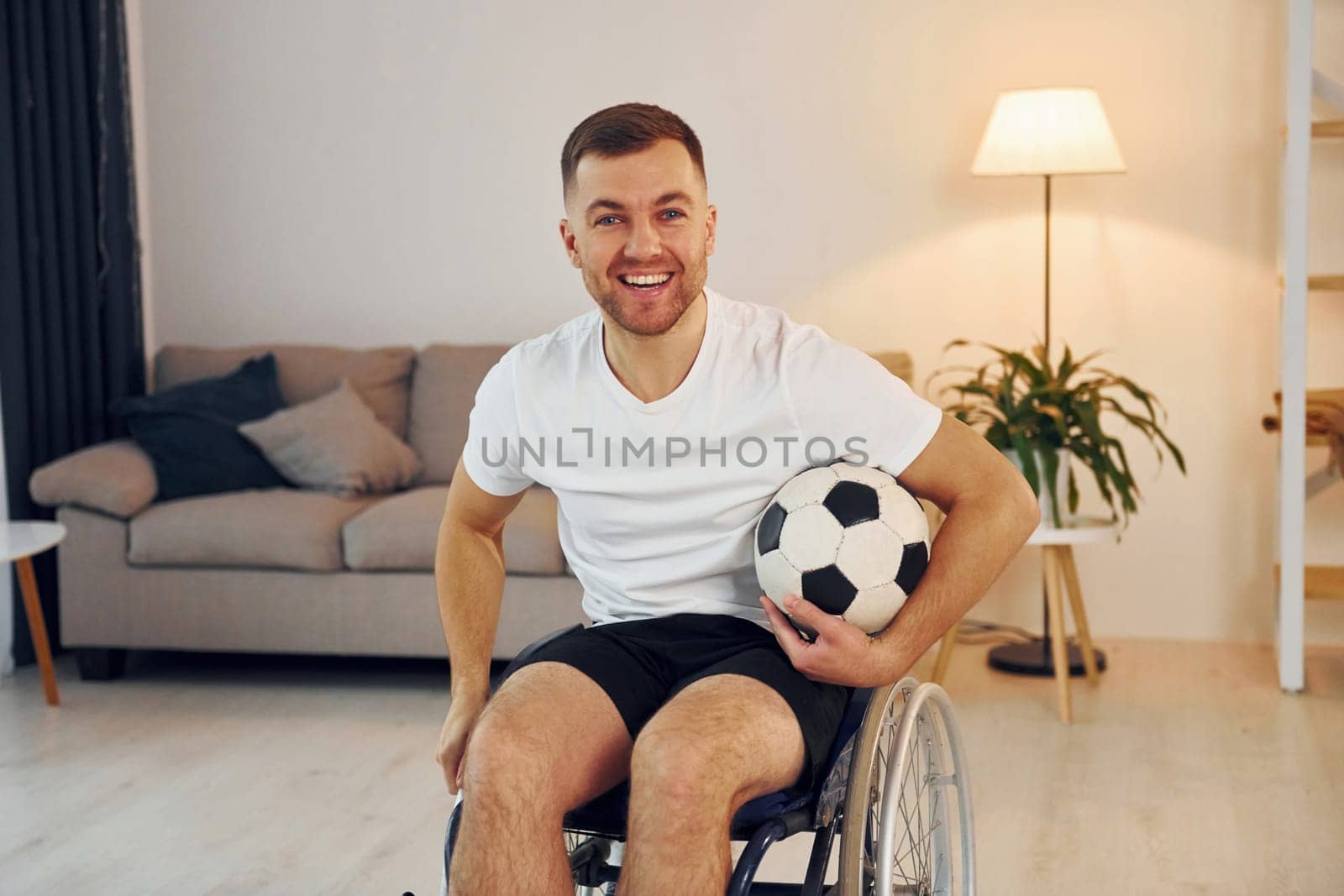 Soccer fan with ball. Disabled man in wheelchair is at home.