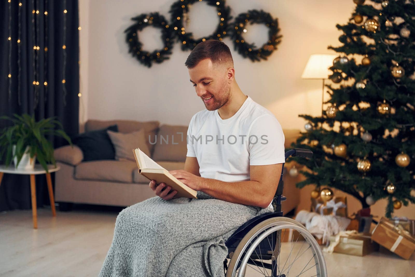 Reading the book. New year is coming. Disabled man in wheelchair is at home.