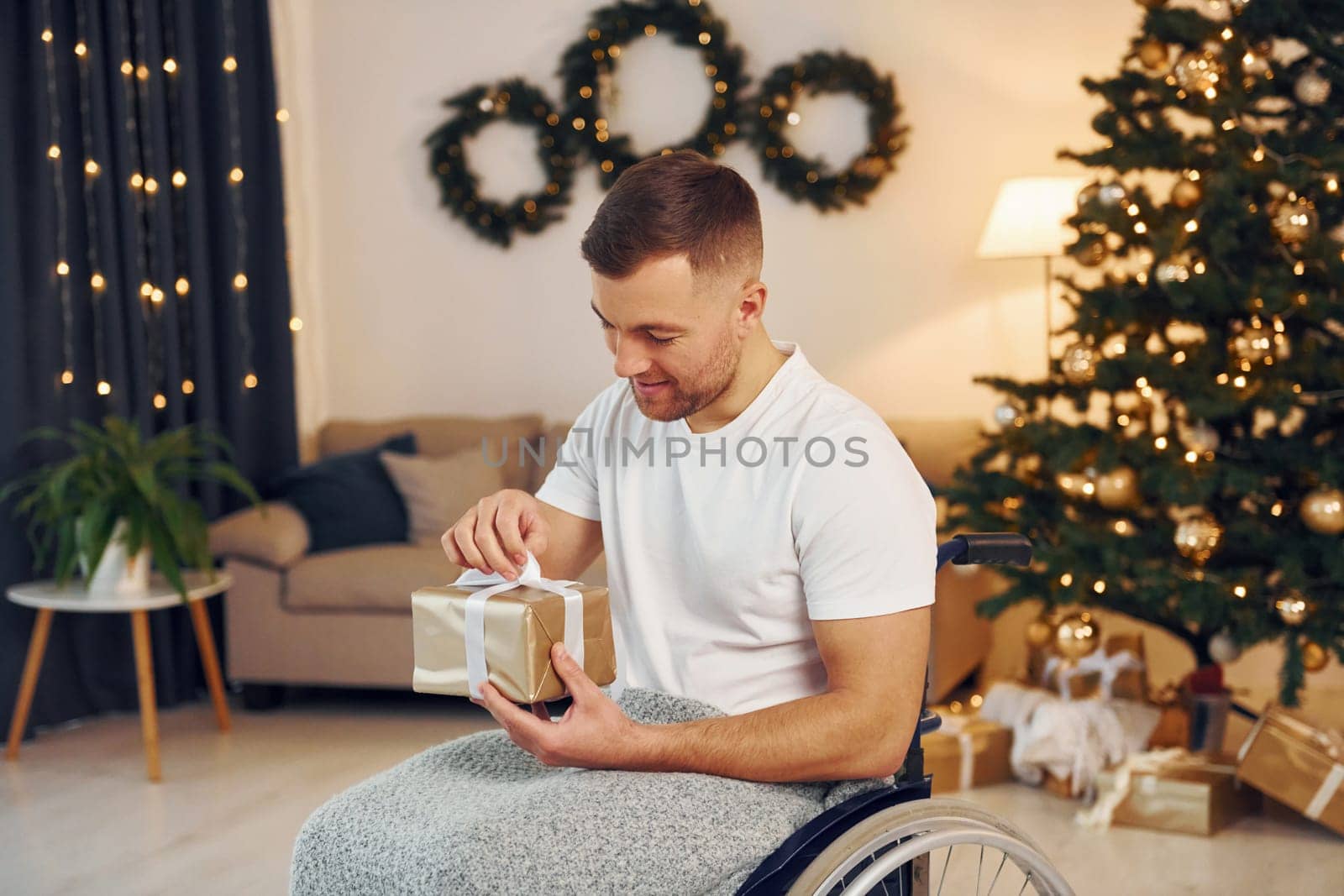 Unboxing preset. New year is coming. Disabled man in wheelchair is at home.