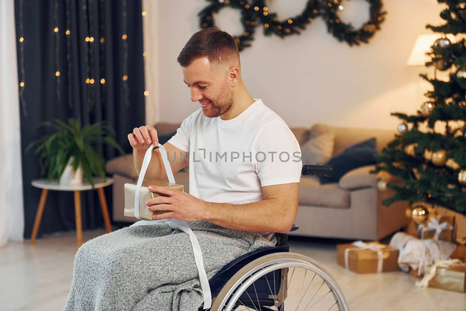 Unboxing preset. New year is coming. Disabled man in wheelchair is at home.