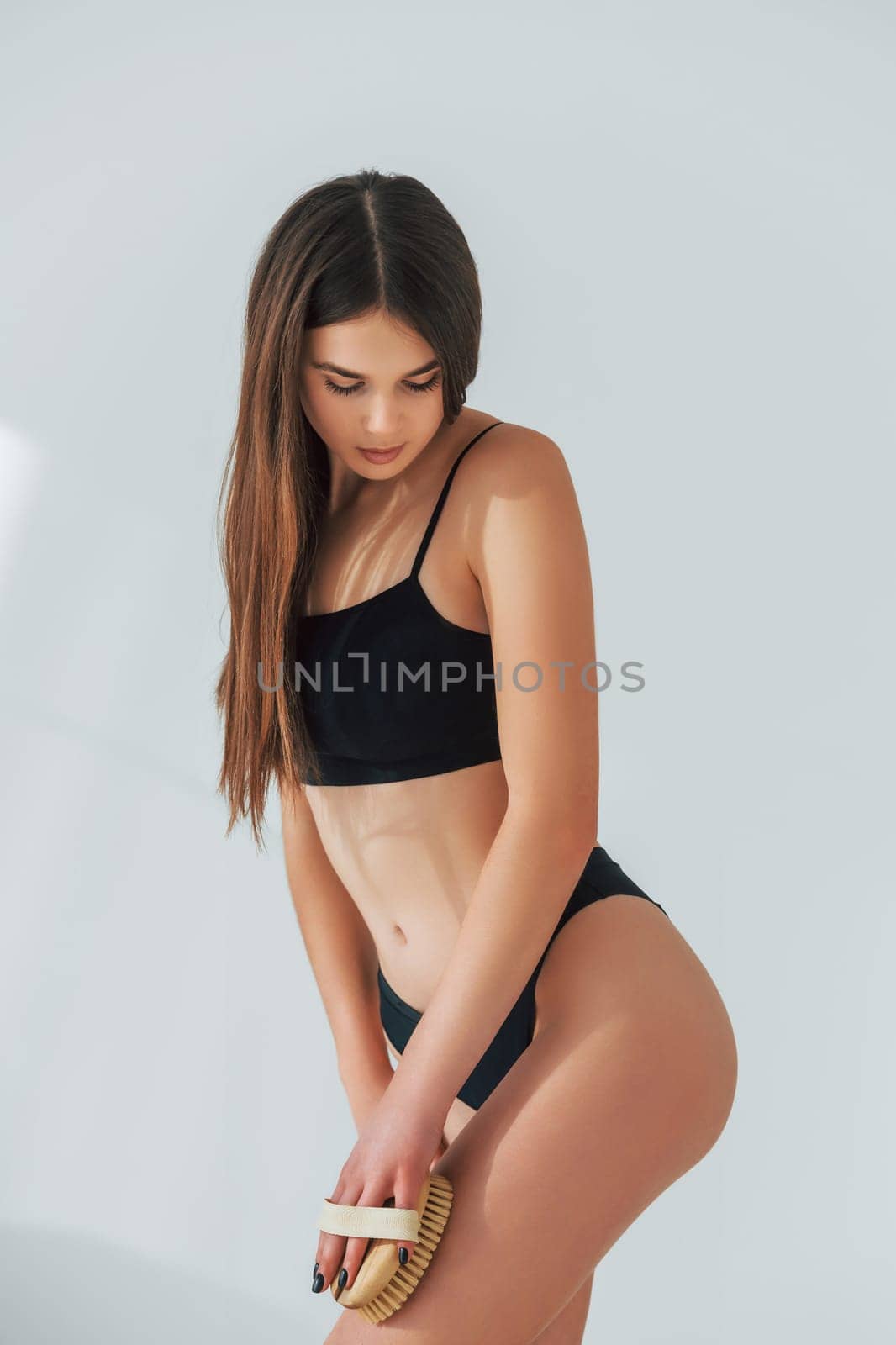 Standing against white background. Beautiful woman in underwear is posing indoors.