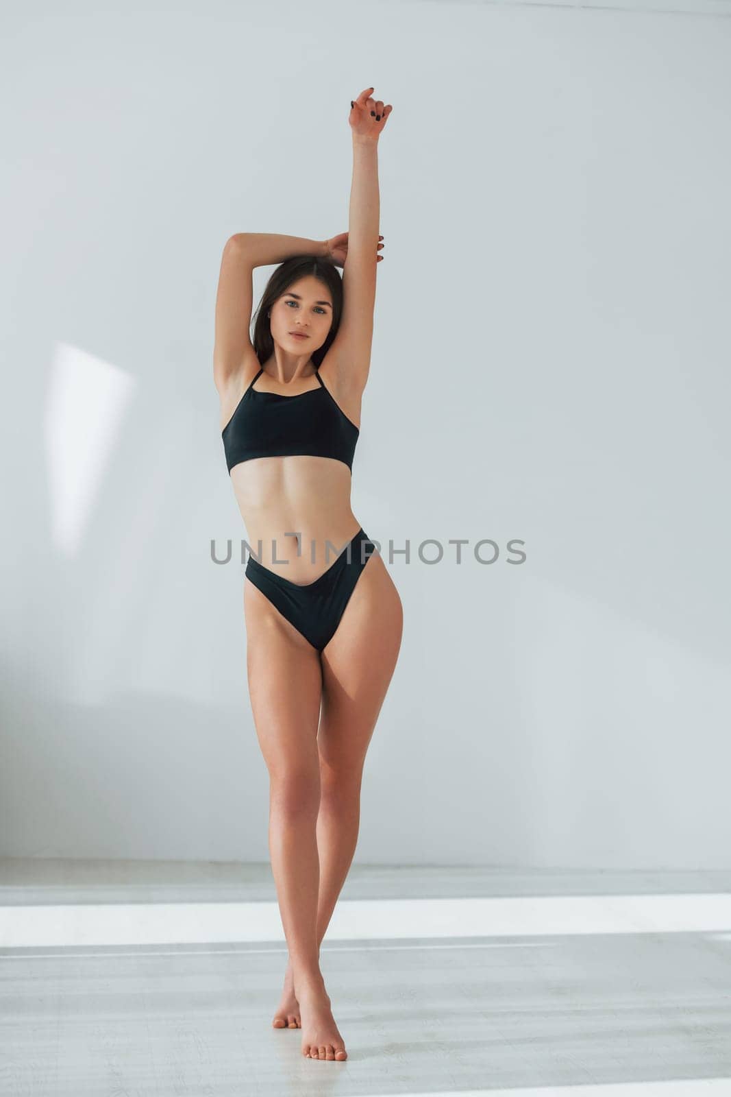 Standing against white background. Beautiful woman in underwear is posing indoors.
