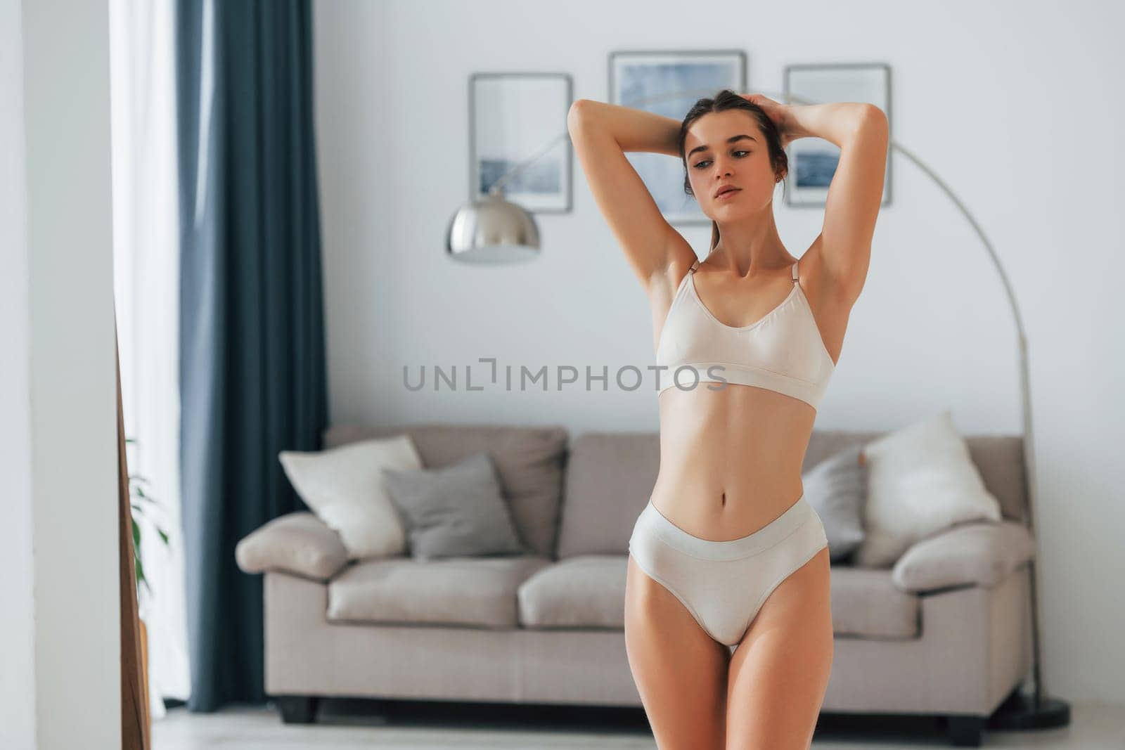 Holding hair. Beautiful woman in underwear is posing indoors.