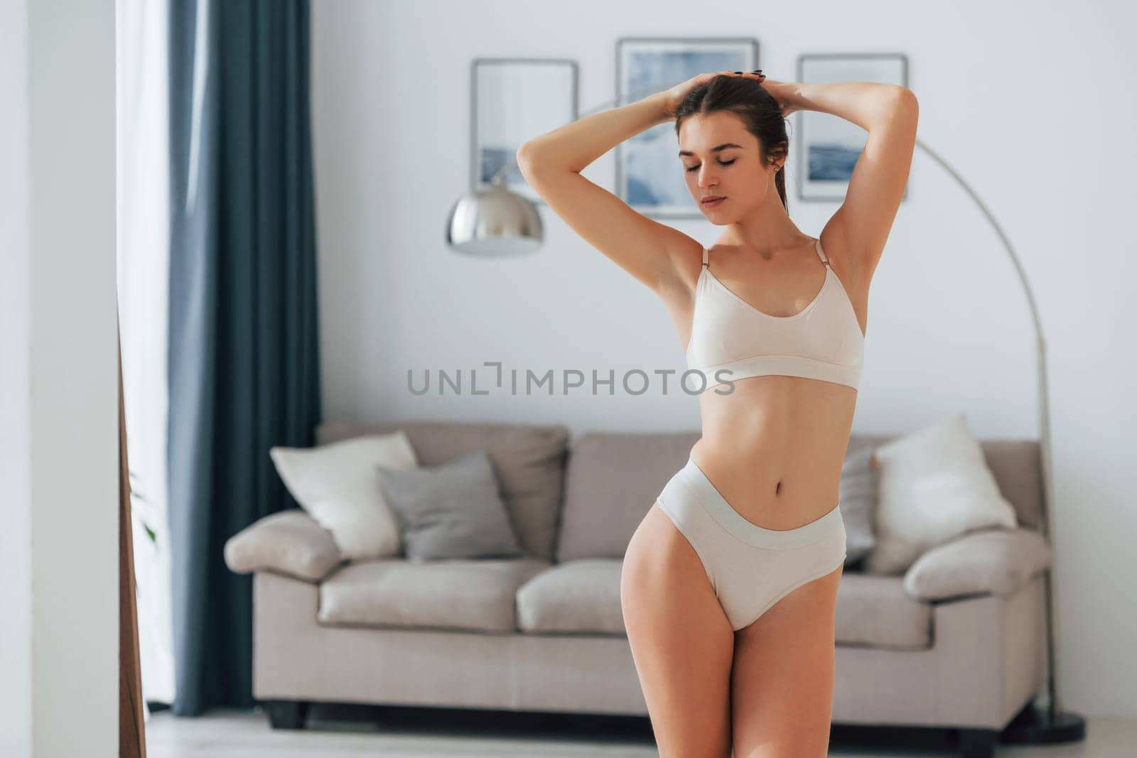 Holding hair. Beautiful woman in underwear is posing indoors.