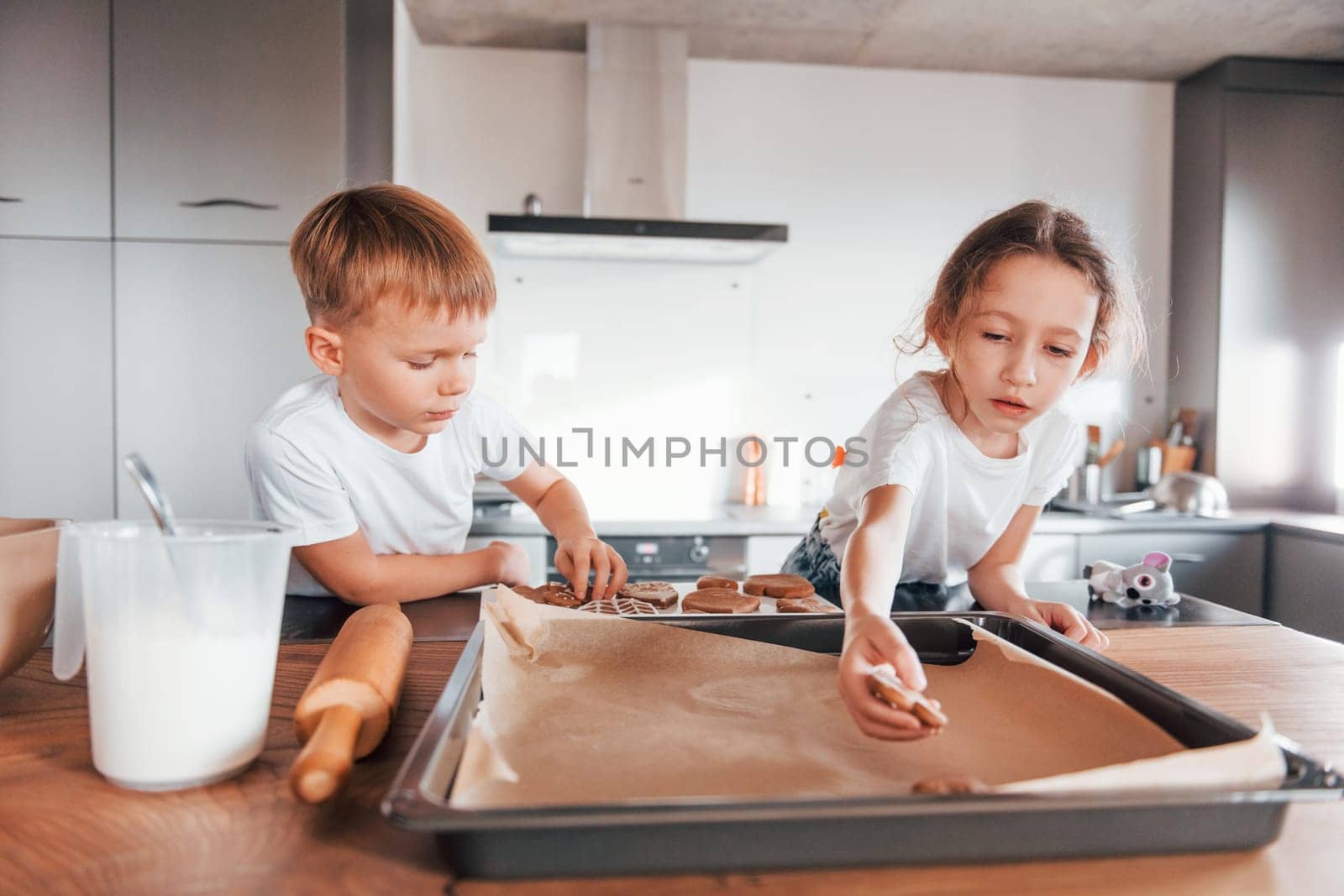 Brother and sister helping each other. Little boy and girl preparing Christmas cookies on the kitchen by Standret