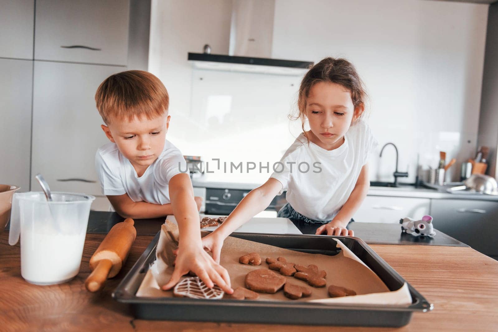 Brother and sister helping each other. Little boy and girl preparing Christmas cookies on the kitchen.