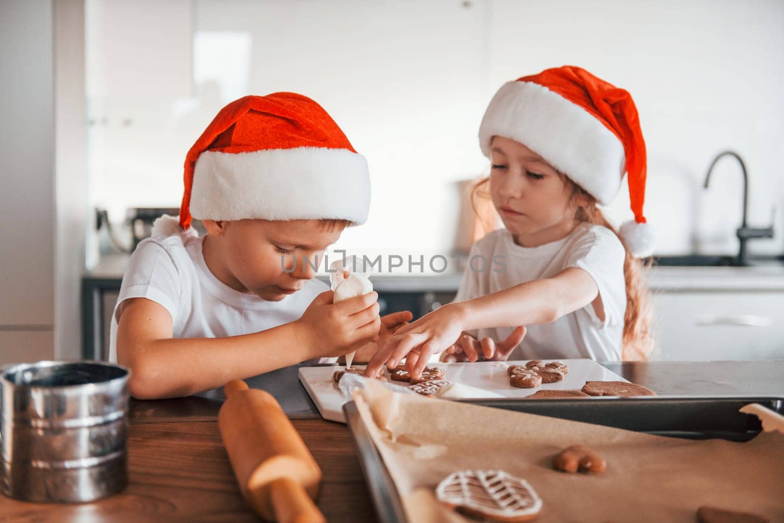 New year anticipation. Little boy and girl preparing Christmas cookies on the kitchen by Standret