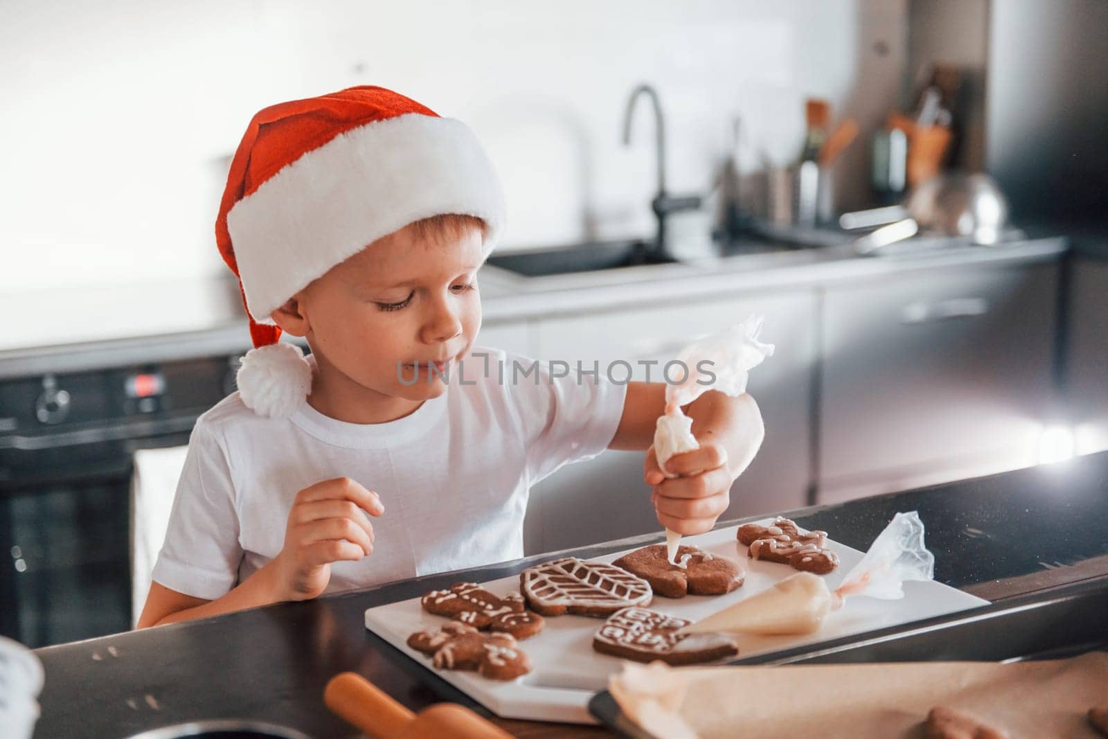 Little boy preparing Christmas cookies on the kitchen.