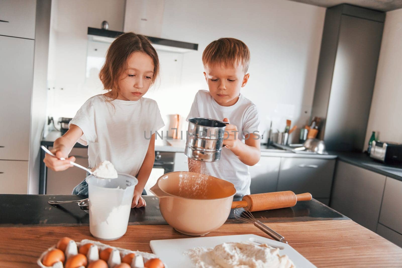 New year anticipation. Little boy and girl preparing Christmas cookies on the kitchen by Standret