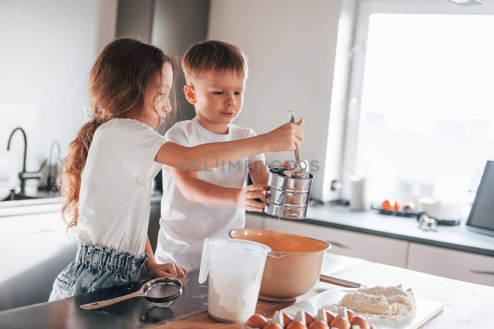 New year anticipation. Little boy and girl preparing Christmas cookies on the kitchen.