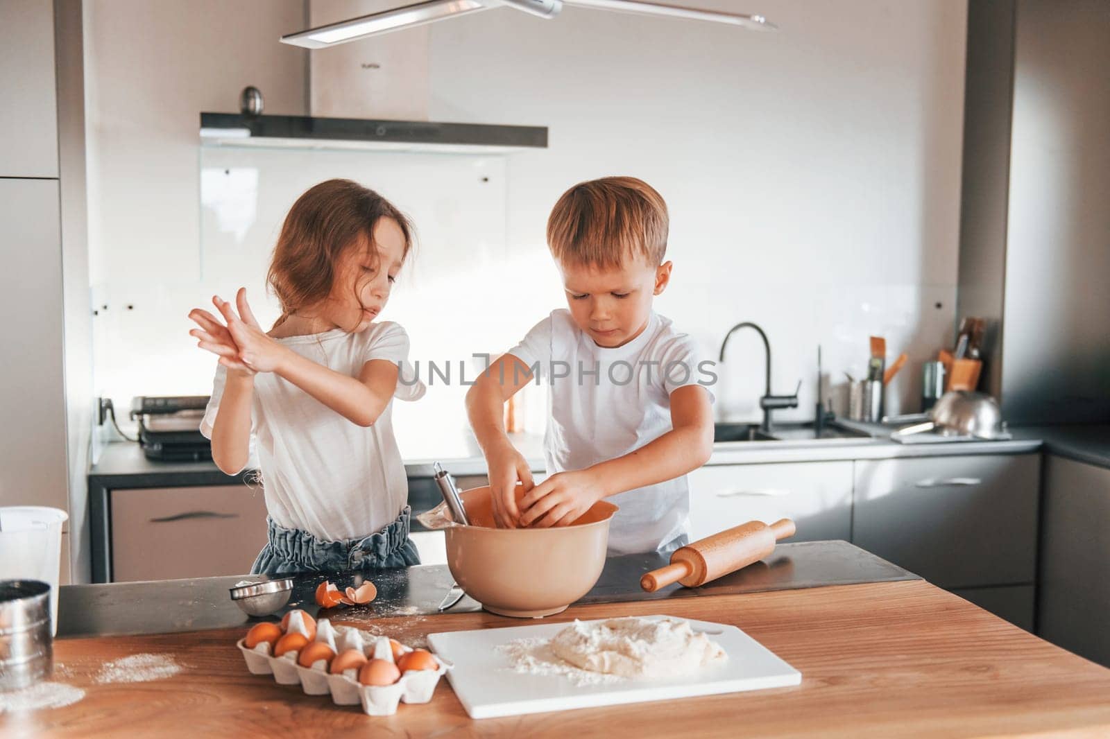 Working with dough. Little boy and girl preparing Christmas cookies on the kitchen.