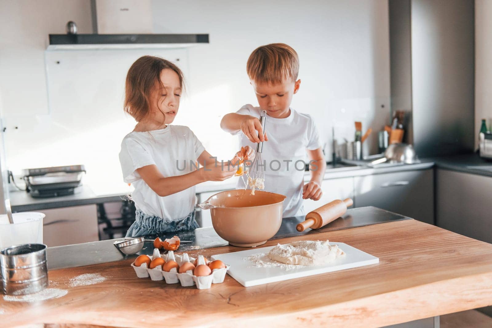 Working with dough. Little boy and girl preparing Christmas cookies on the kitchen.