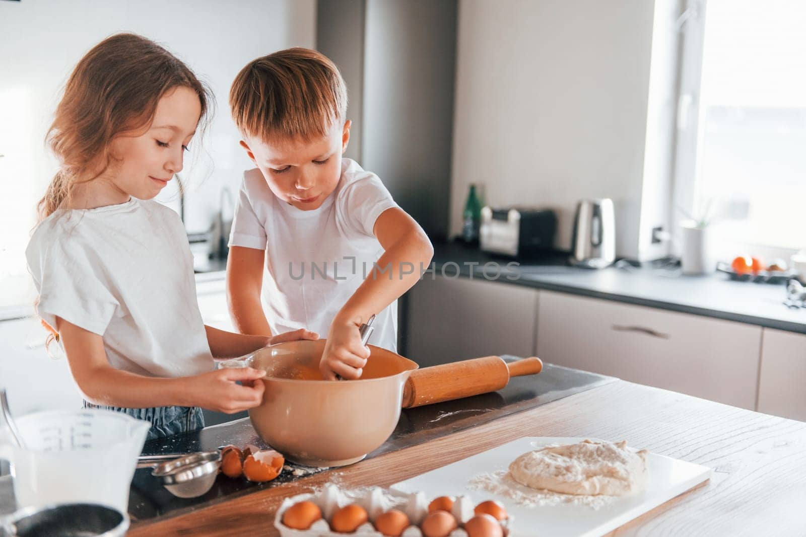 Preparing food together. Little boy and girl on the kitchen.