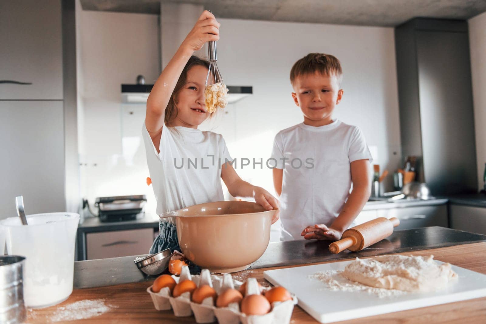 Weekend activities. Little boy and girl preparing Christmas cookies on the kitchen by Standret