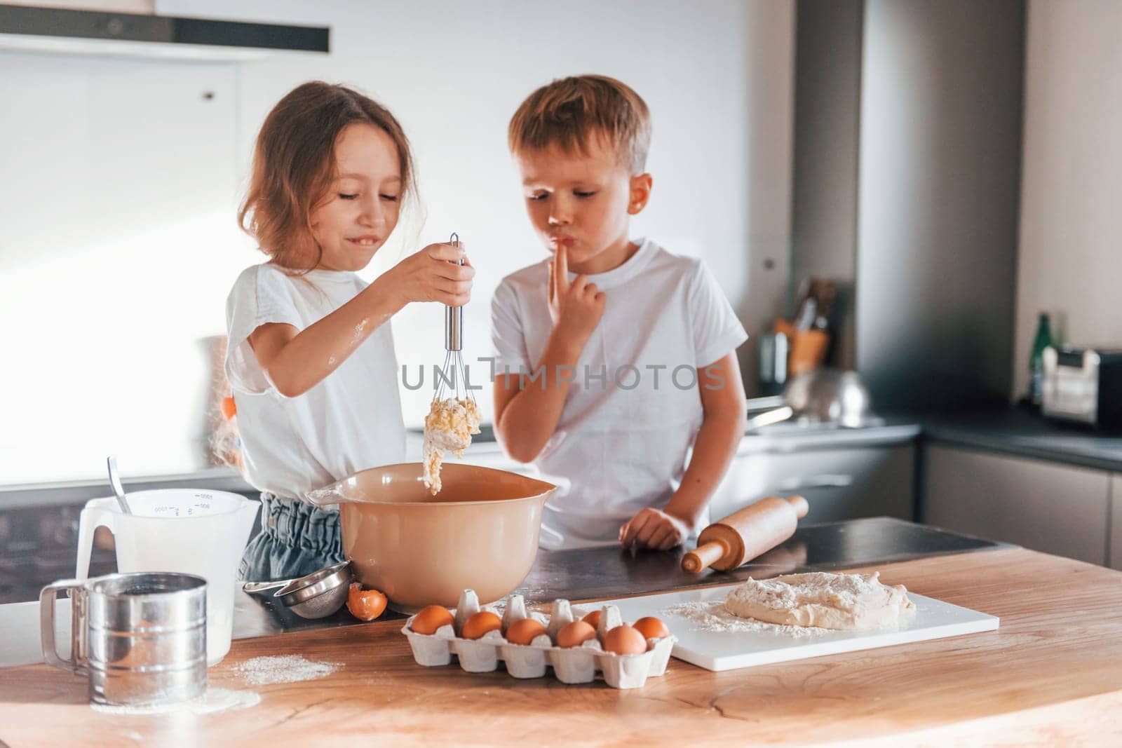 Weekend activities. Little boy and girl preparing Christmas cookies on the kitchen.