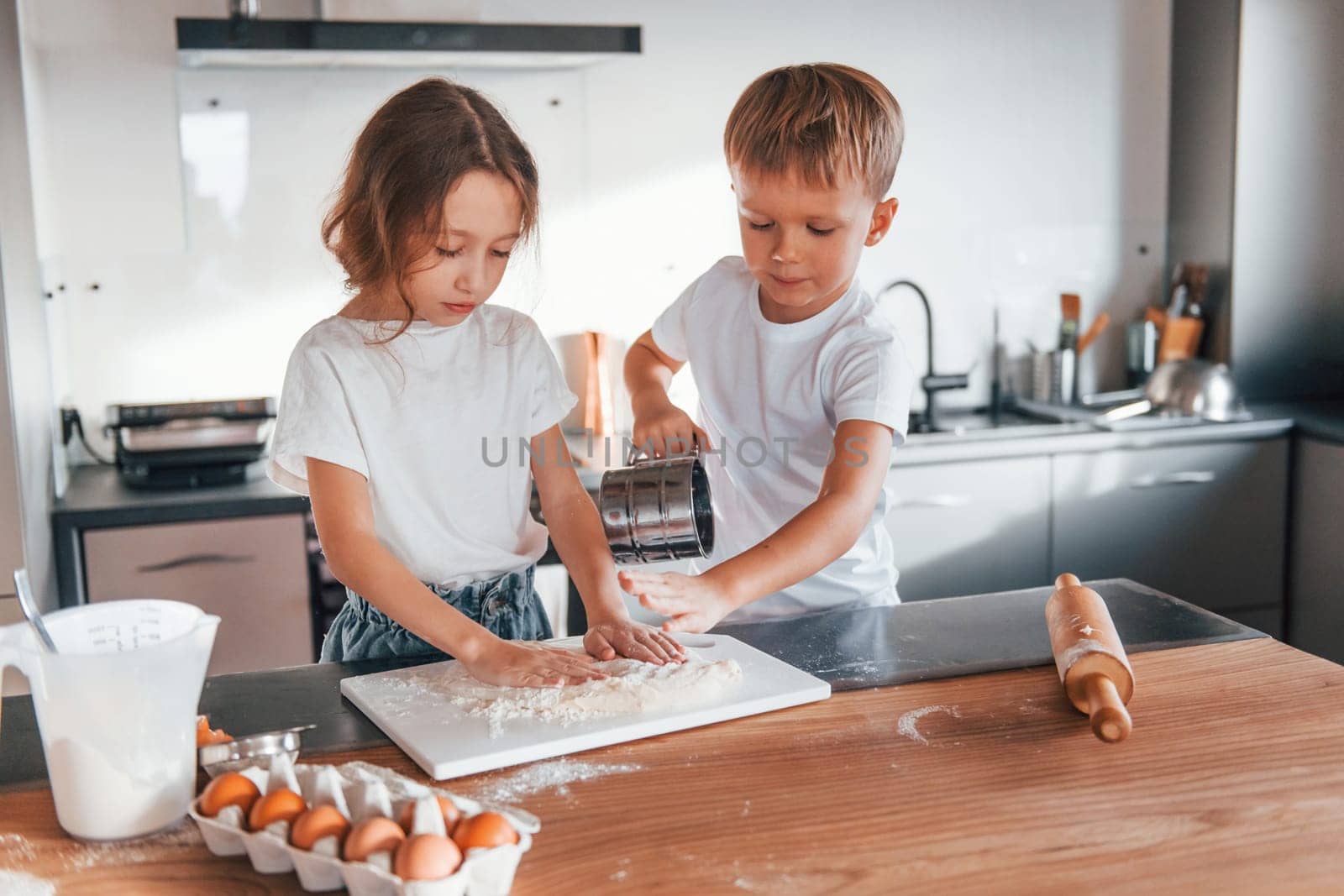 Weekend activities. Little boy and girl preparing Christmas cookies on the kitchen.