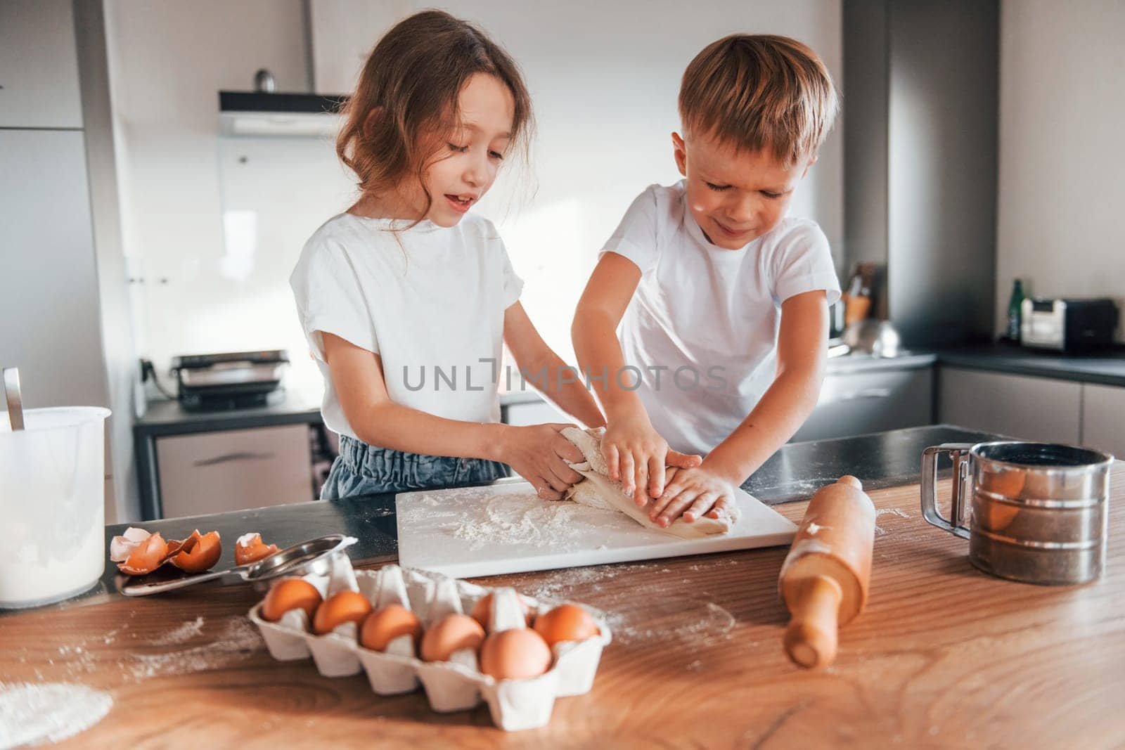 Cheerful emotions. Little boy and girl preparing Christmas cookies on the kitchen by Standret