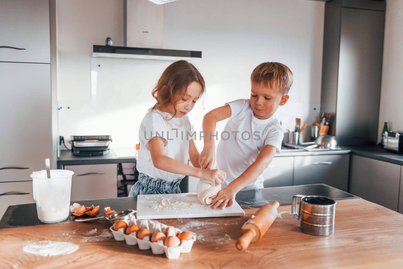 Cheerful emotions. Little boy and girl preparing Christmas cookies on the kitchen.