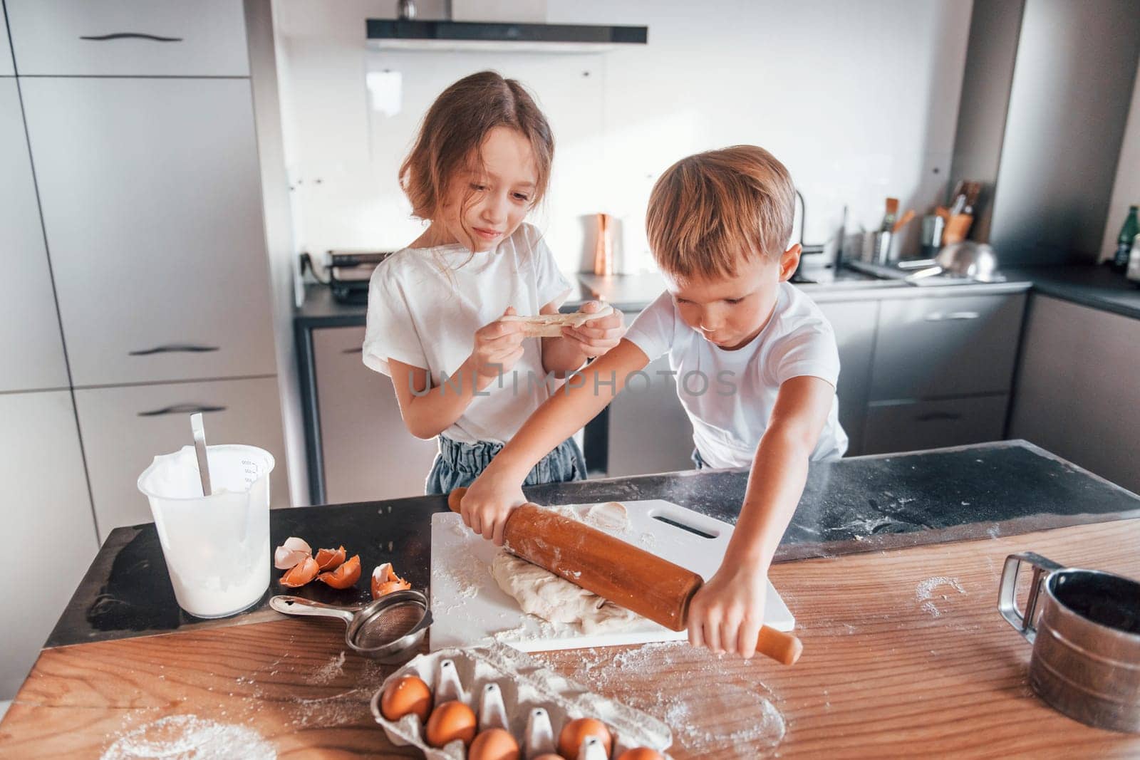 Two people together. Little boy and girl preparing Christmas cookies on the kitchen.