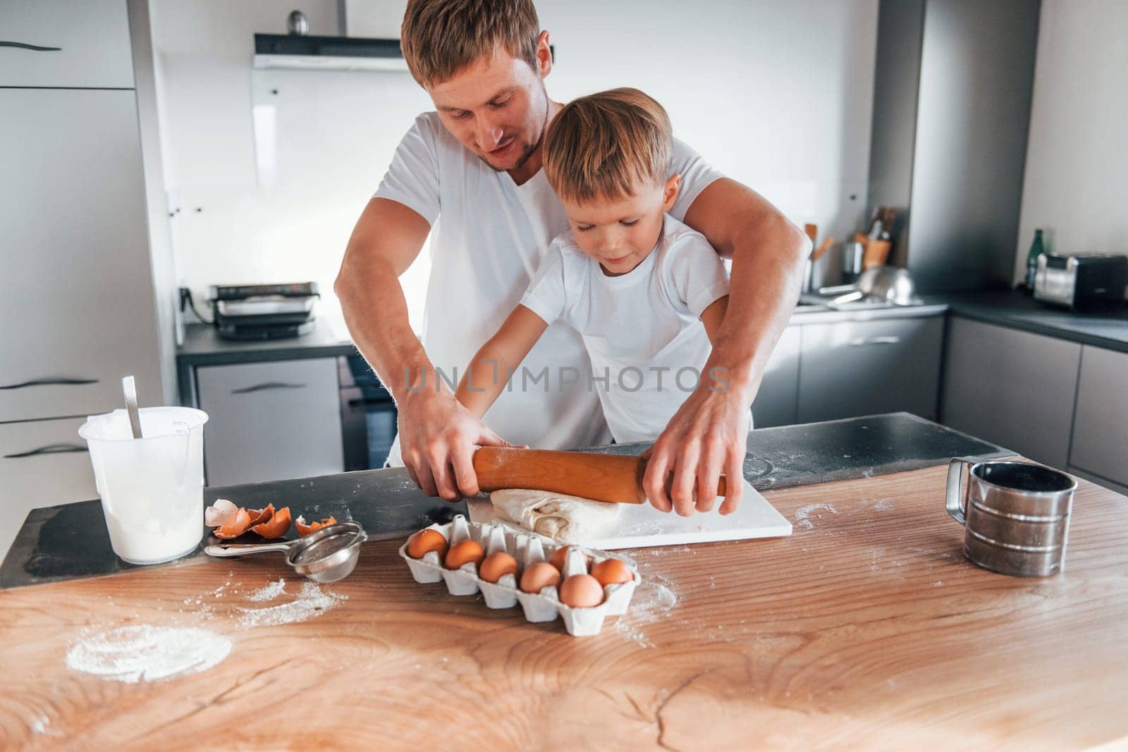 Little helper. Father teaching his little son with preparing of sweet christmas cookies.