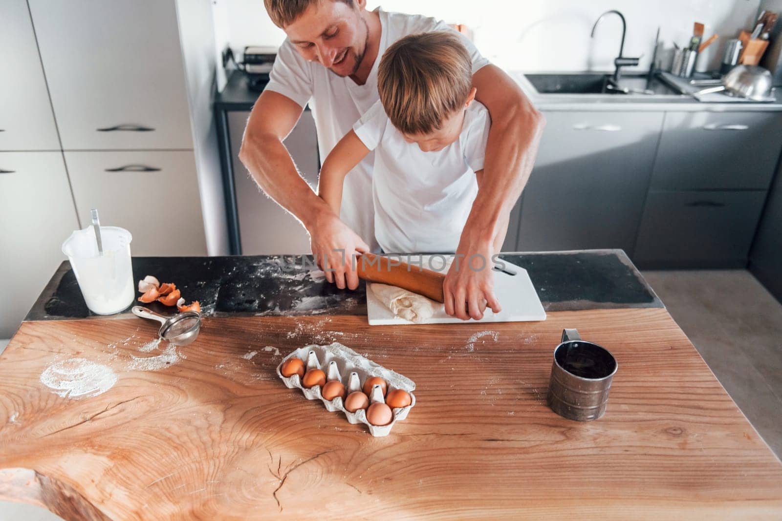 Little helper. Father teaching his little son with preparing of sweet christmas cookies.