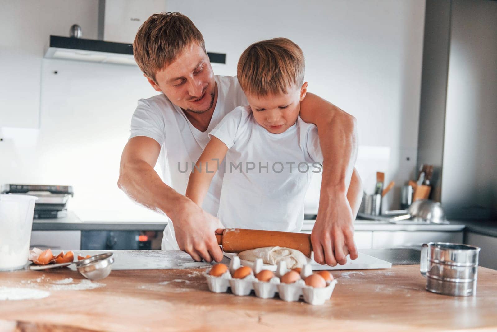 Little helper. Father teaching his little son with preparing of sweet christmas cookies.