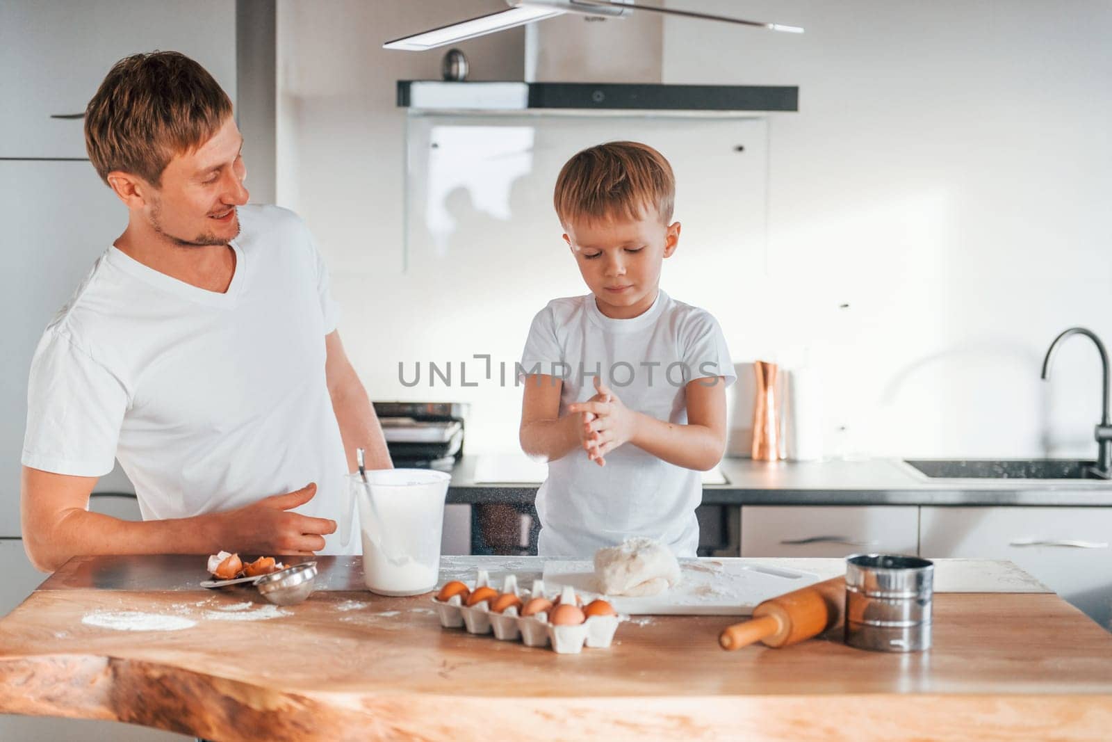 Eggs, milk and dough. Father teaching his little son with preparing of sweet christmas cookies.