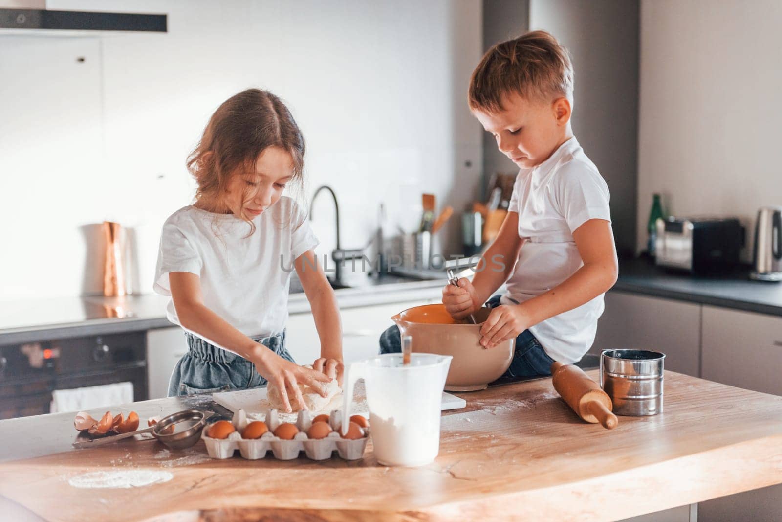 Two people together. Little boy and girl preparing Christmas cookies on the kitchen.