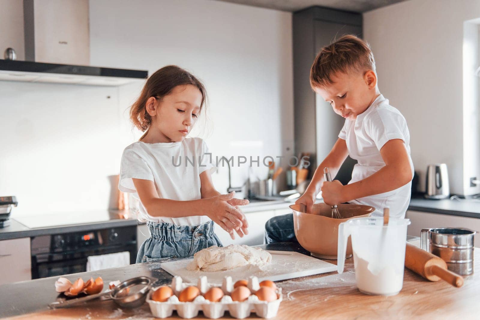 Making sweets. Little boy and girl preparing Christmas cookies on the kitchen by Standret