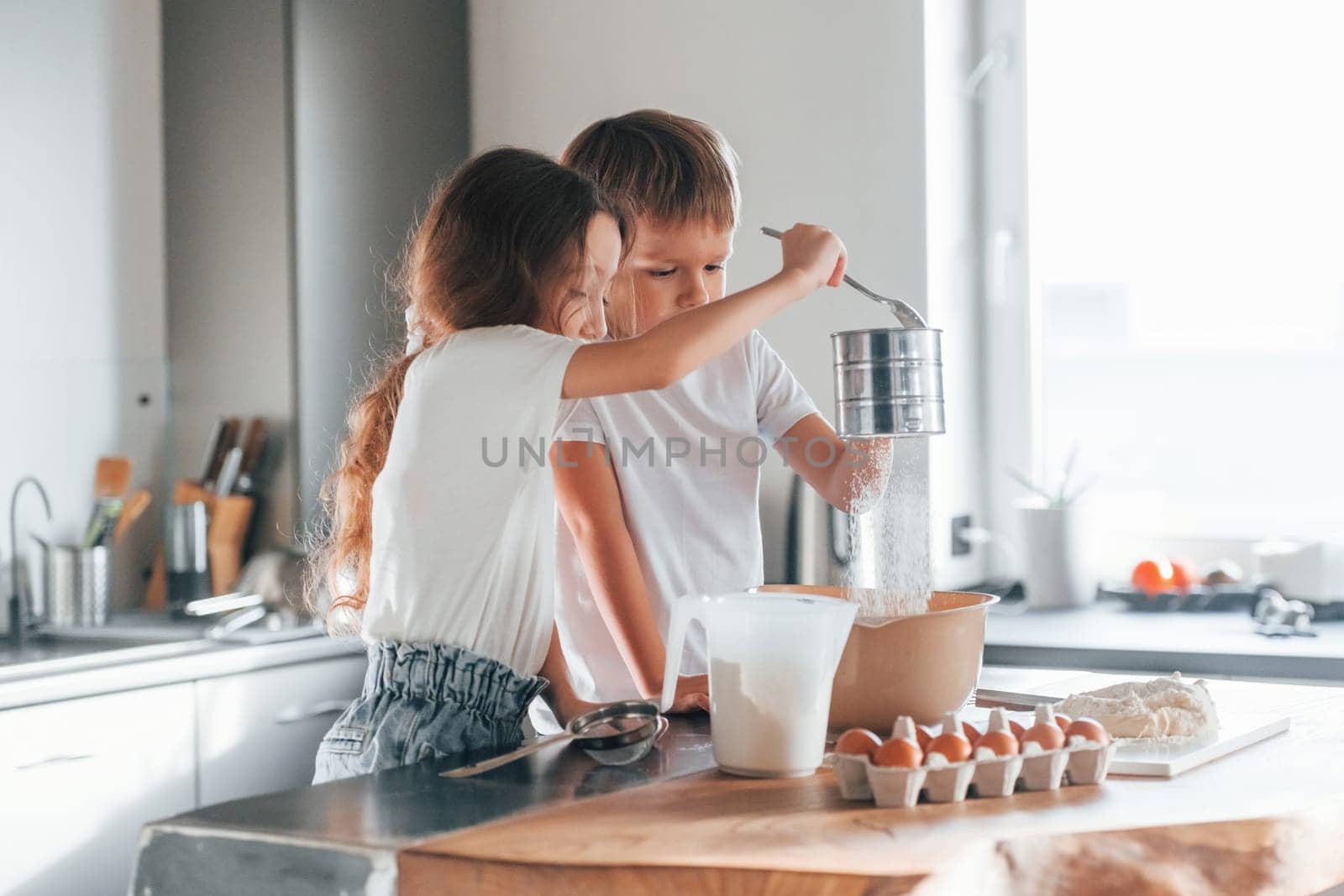 Pouring water. Little boy and girl preparing Christmas cookies on the kitchen.