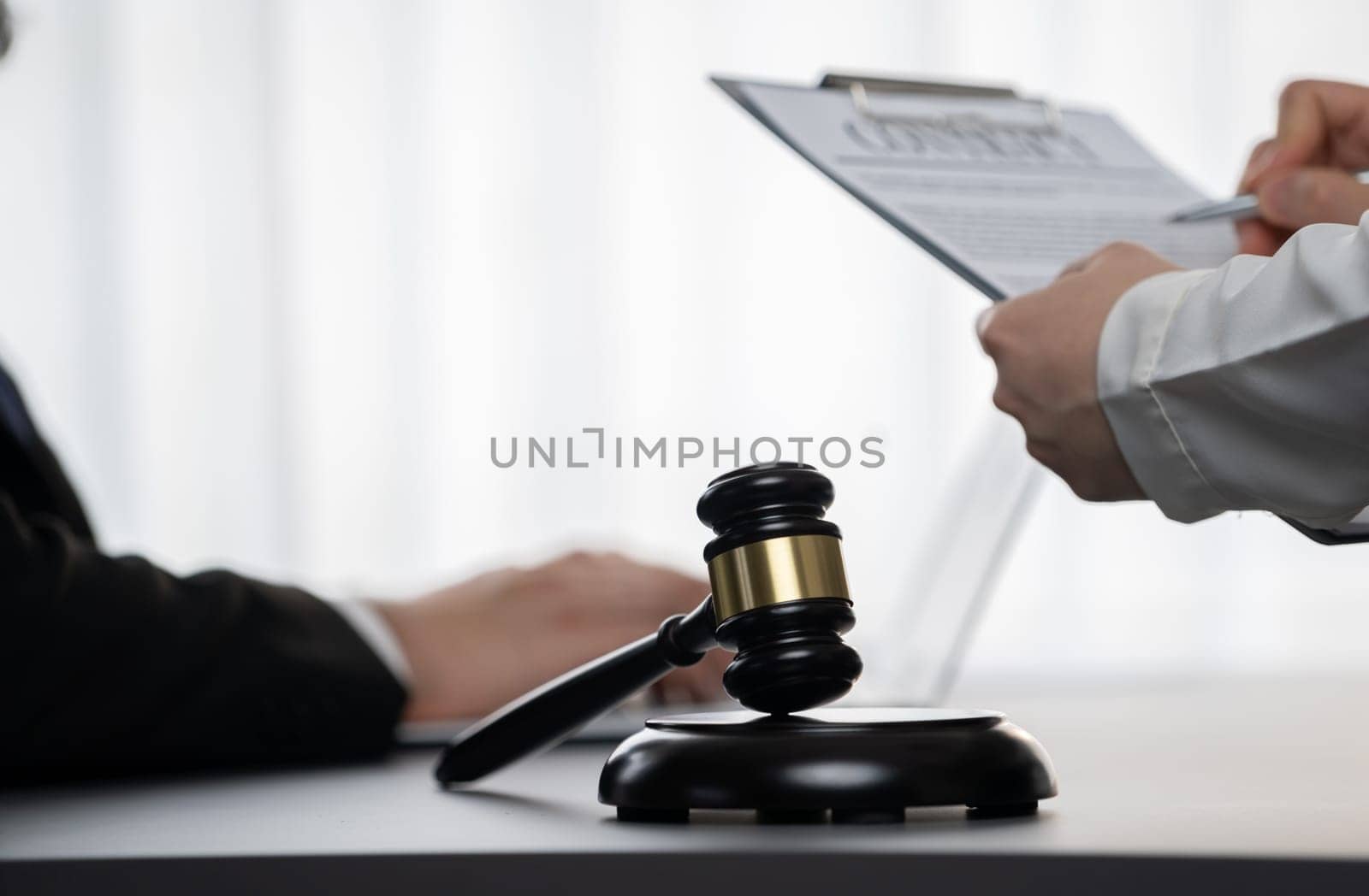 Focus gavel hammer for righteous and equality judgment with blur background of lawyer colleagues or legal team working with laptop, drafting legal documents for litigation at law firm. Equilibrium