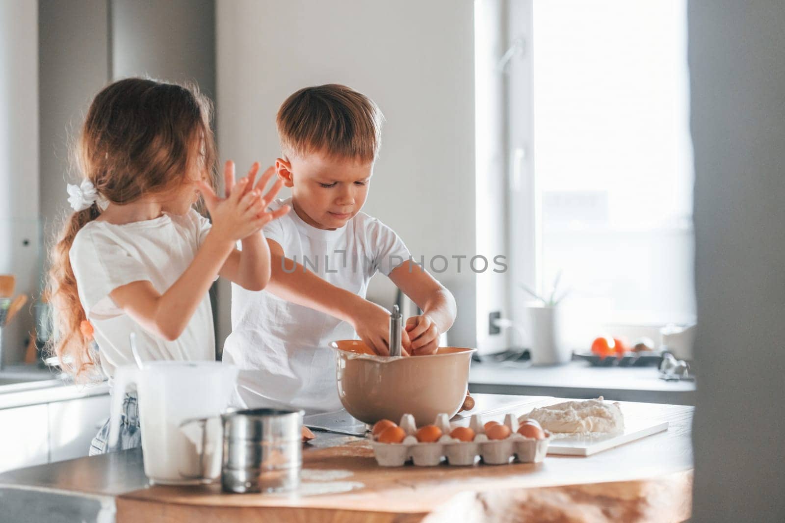 At daytime. Little boy and girl preparing Christmas cookies on the kitchen by Standret