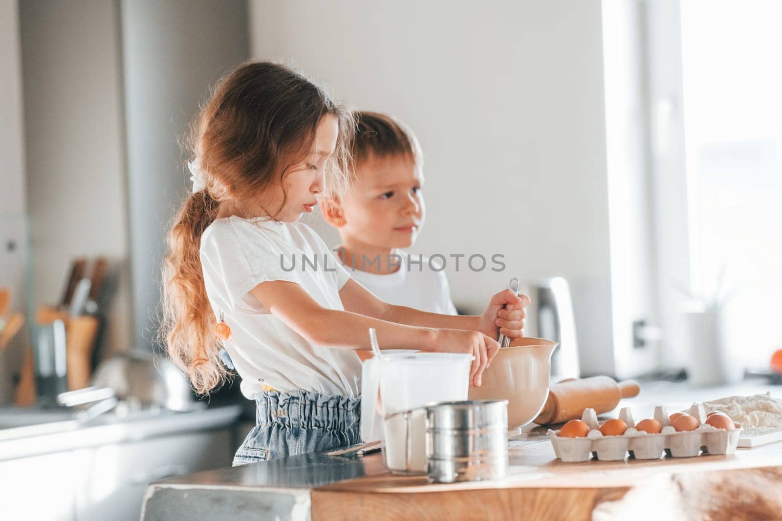 Learning how to cook. Little boy and girl preparing Christmas cookies on the kitchen.