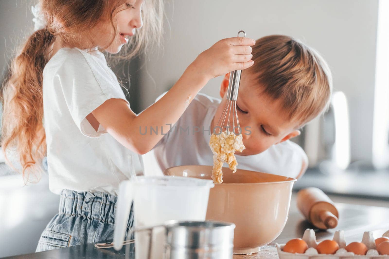 Learning how to cook. Little boy and girl preparing Christmas cookies on the kitchen.