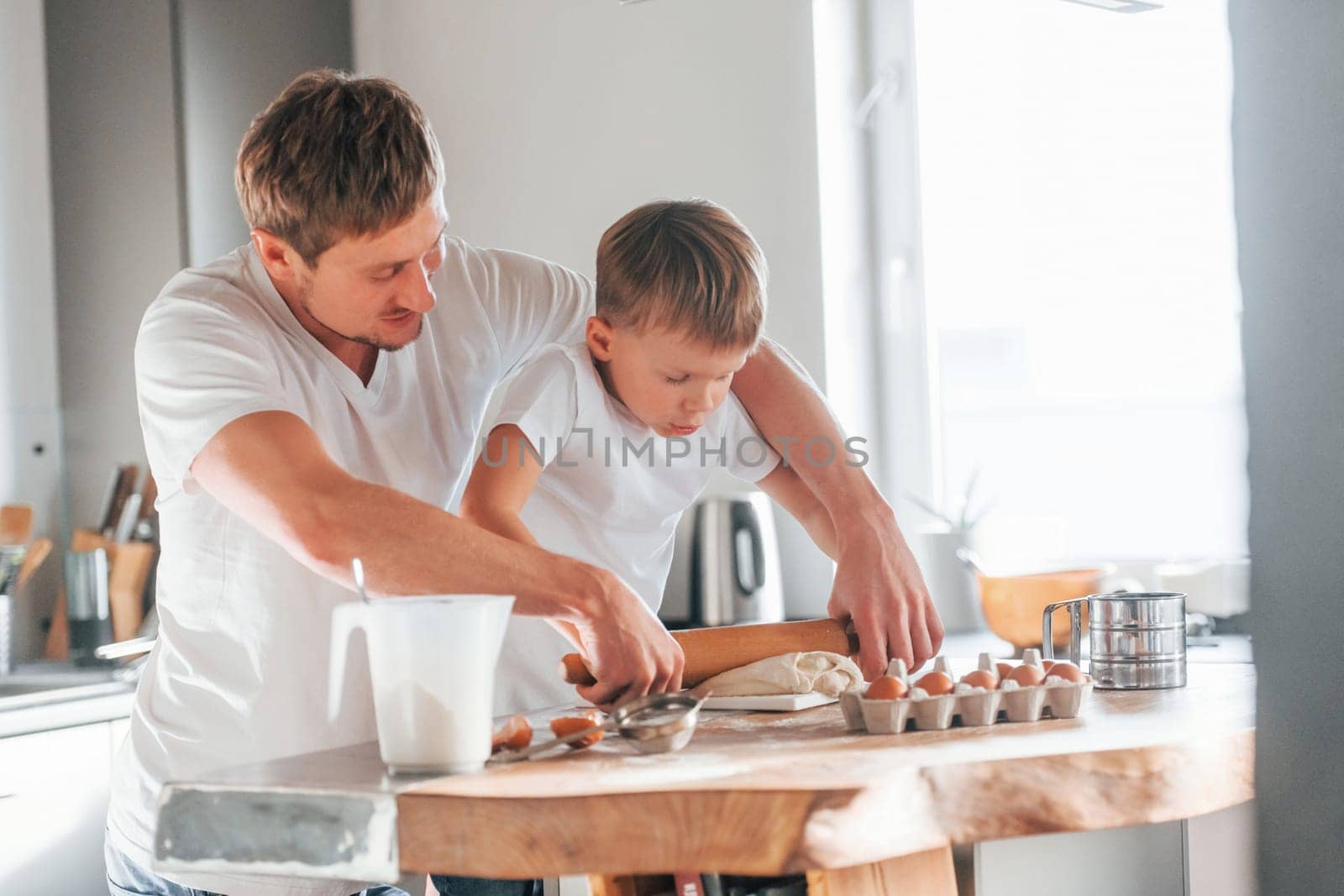 Father teaching his little son with preparing of sweet christmas cookies.
