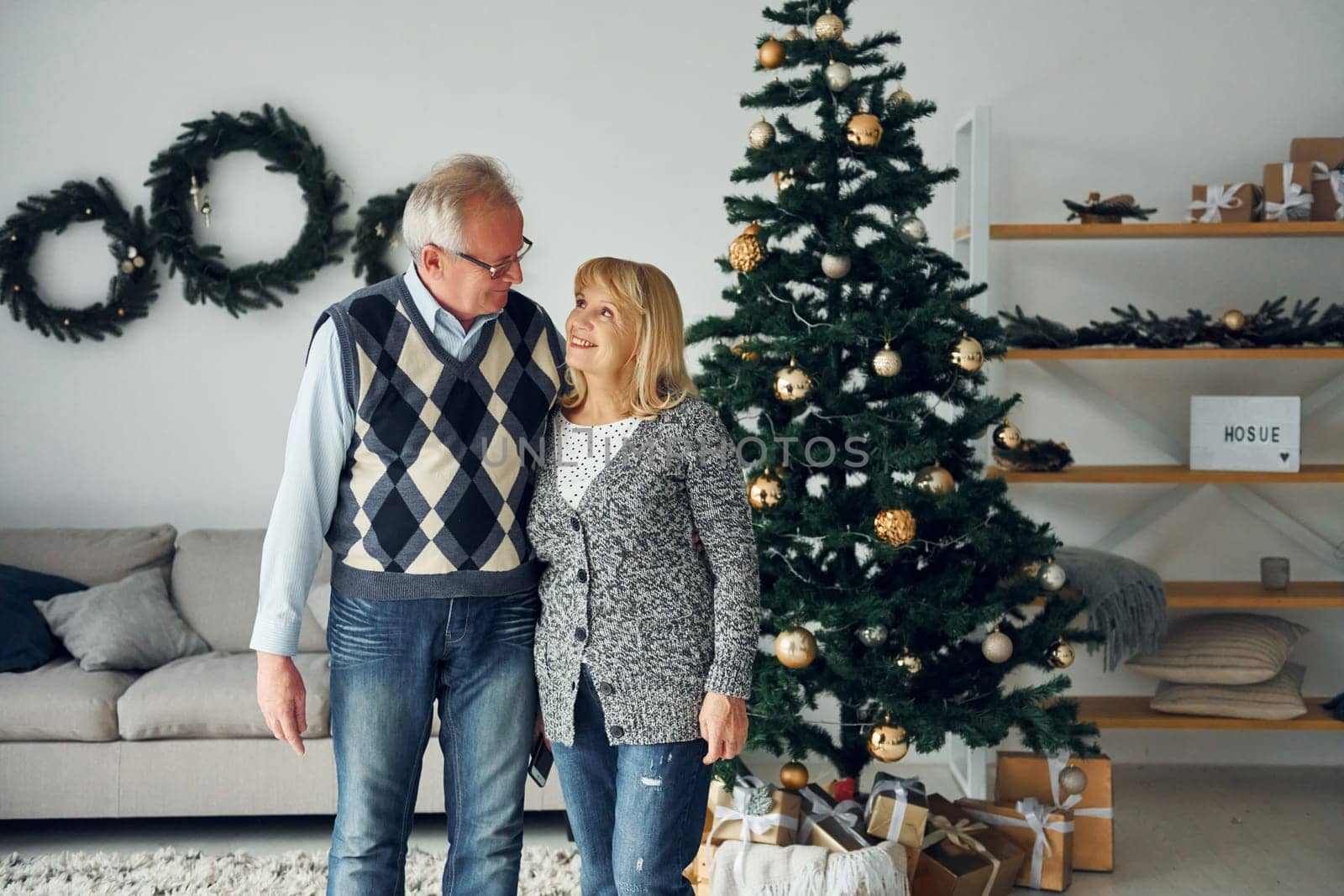 Standing near christmas tree. Senior man and woman is together at home.