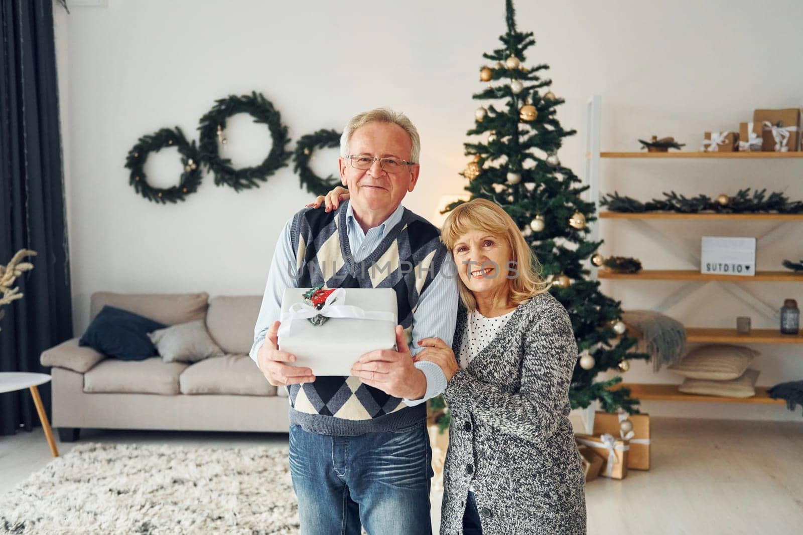 Standing near christmas tree. Senior man and woman is together at home.