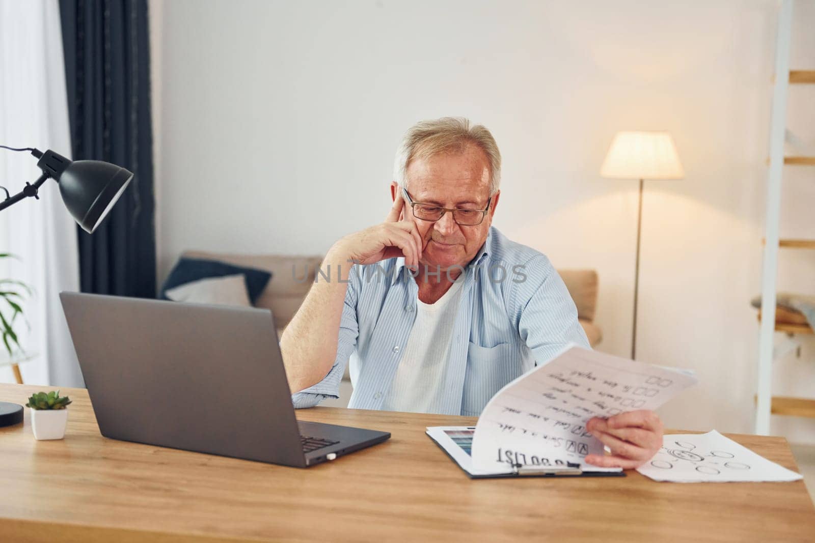 Working by using laptop. Senior man in nice clothes is at home.